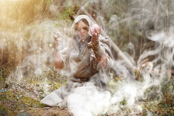 Een man in een soutane besteedt een ritueel in een donker bos — Stockfoto