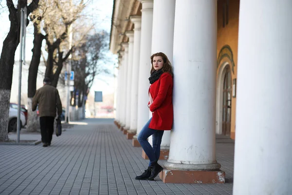 Красивая девушка на прогулке в красном пальто в городе — стоковое фото