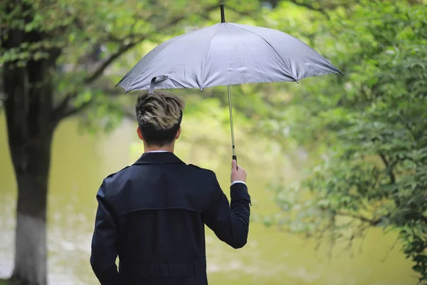 Spring rainy weather and a young man with an umbrella — Stock Photo, Image
