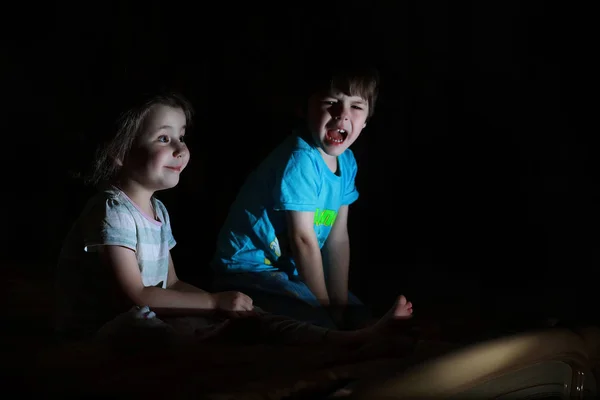 Niños pequeños en una habitación oscura viendo la televisión —  Fotos de Stock