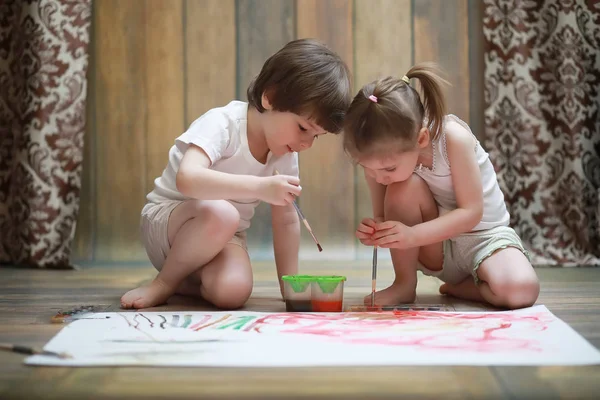 Niños pequeños pintan en una hoja grande de papel —  Fotos de Stock