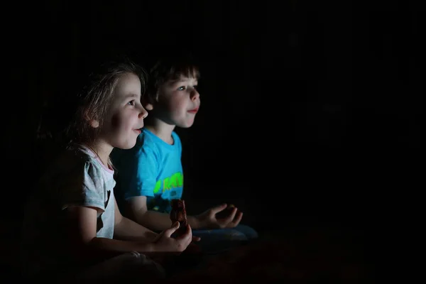 Niños pequeños en una habitación oscura viendo la televisión —  Fotos de Stock