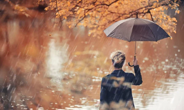 Herbstliches Regenwetter und ein junger Mann mit Regenschirm — Stockfoto