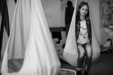 Çocuk odasında bir çocuk var. Çocuk pencerede oturuyor.