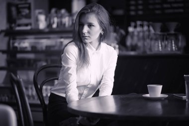 Bir kız bir kafede kahve içiyor. Bir kadın kahvaltı yapıyor