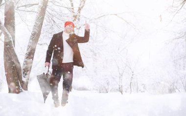 Parkta yürüyen bir adam. Genç adam kışın karla kaplı