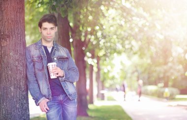 Genç bir adam öğle yemeği zamanında parkta yürür. Bir adam şehirde gezintiye çıktı. Park eden bir öğrenci.