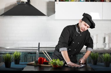 Adam mutfak masasında sebze pişiriyor.