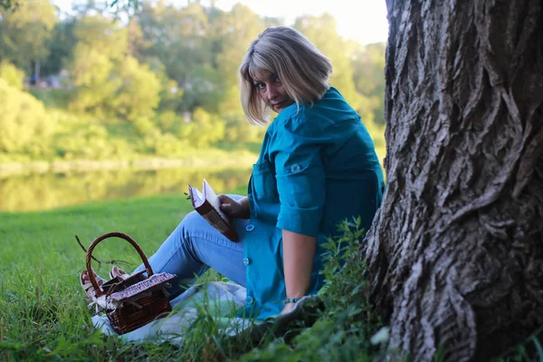 Kobieta w parku z książki na trawie — Zdjęcie stockowe