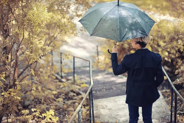 Herbstliches Regenwetter und ein junger Mann mit Regenschirm — Stockfoto