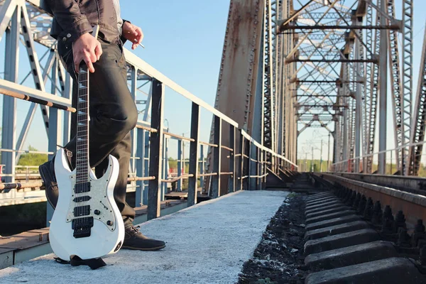 Hombre con una guitarra eléctrica en el paisaje industrial al aire libre — Foto de Stock