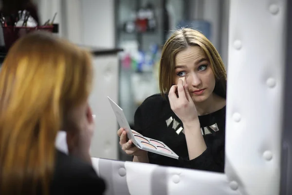 En ung flicka gör make-up i en skönhetssalong. Flickan i receptionen o — Stockfoto