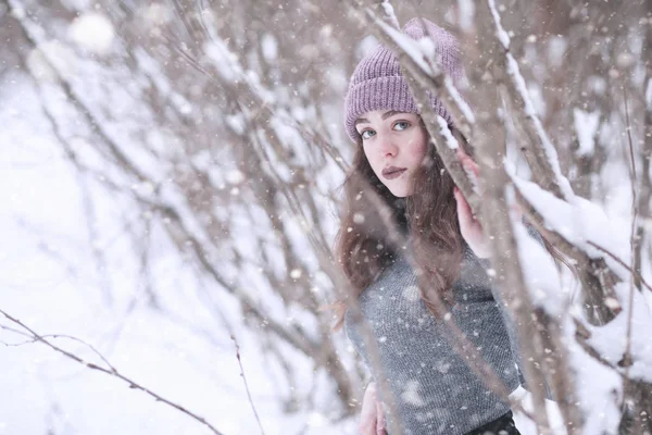 Menina em um parque de inverno na queda de neve — Fotografia de Stock