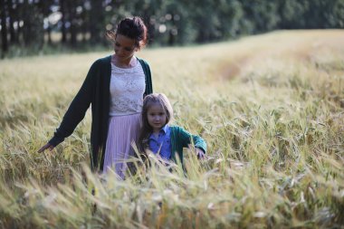 Genç anne yürüyerek buğday alanları içerisinde