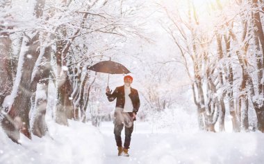 Parkta yürüyen bir adam. Genç adam kışın karla kaplı