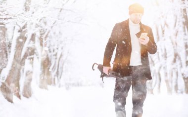 Parkta yürüyen bir adam. Genç adam kışın karla kaplı