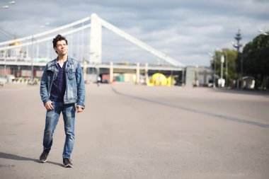 Genç bir adam öğle yemeği zamanında parkta yürür. Bir adam yürüyüşe çıktı. 