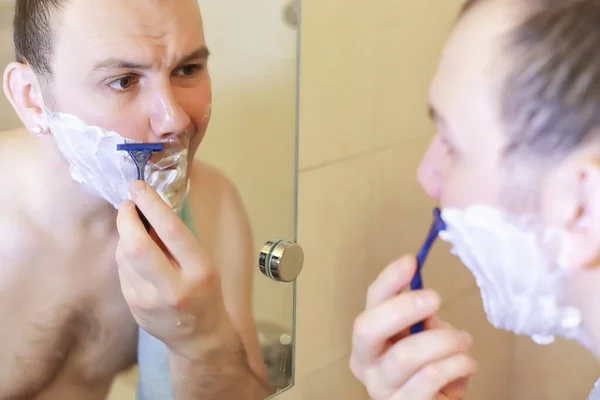 Um homem faz a barba na casa de banho pela manhã — Fotografia de Stock