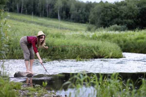 Menina junto ao rio com uma vara de pesca — Fotografia de Stock