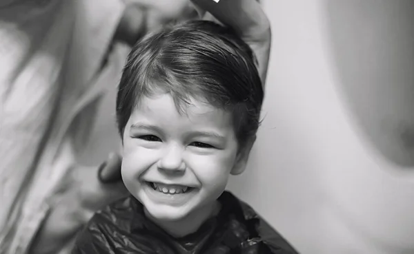 Peluquero y chico. El chico se está peinando. Cortar el pelo niño i — Foto de Stock