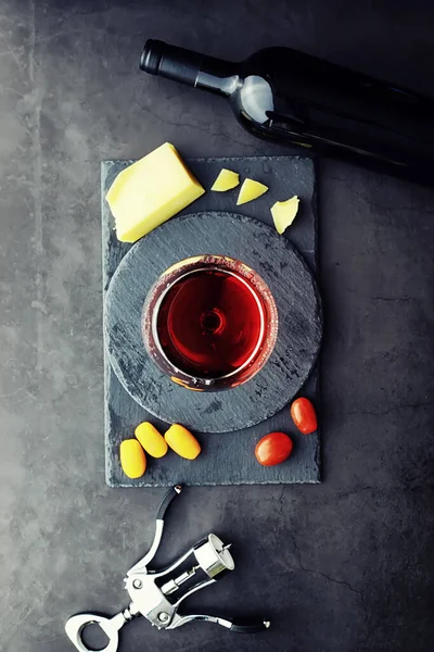 Wine glass and black wine bottle. Nuts cheese and tomatoes for s