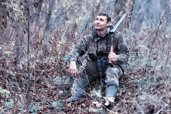 Чоловік в камуфляжі і з мисливською гвинтівкою в лісі на шпилі — стокове фото