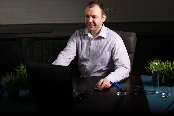 man sitting at table and working on laptop