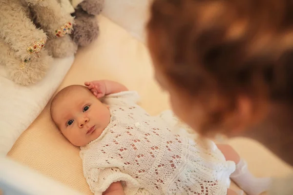 Neonato bambino carino si trova nella culla e guardando la madre — Foto Stock
