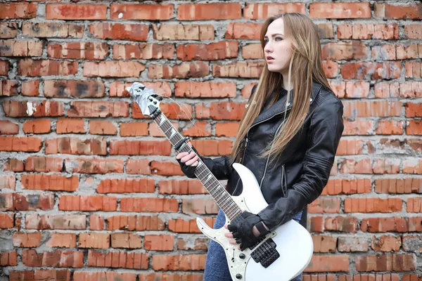 Uma menina músico de rock em uma jaqueta de couro com uma guitarra — Fotografia de Stock