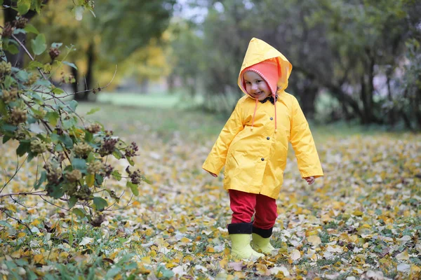 Ett barn i en regnrock för en promenad utanför — Stockfoto