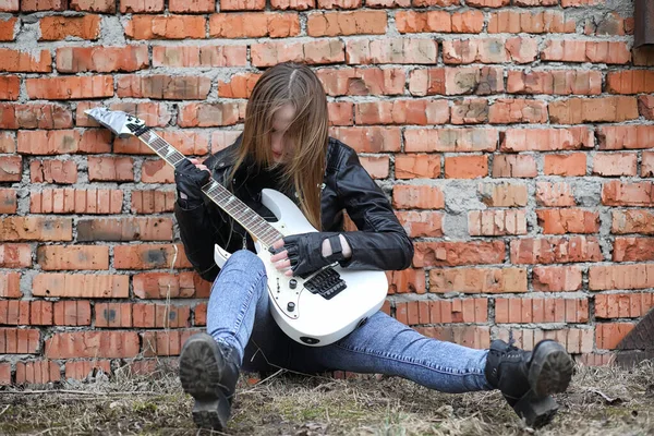 Uma menina músico de rock em uma jaqueta de couro com uma guitarra — Fotografia de Stock