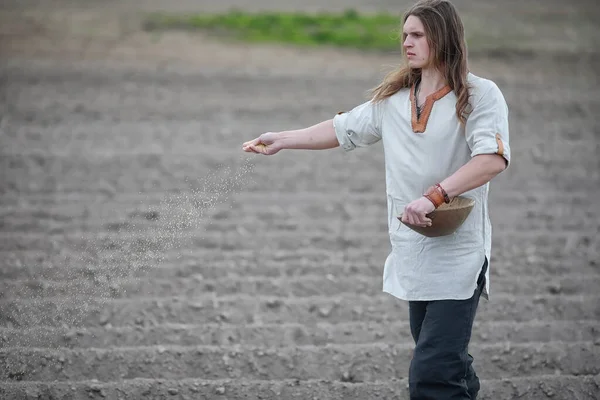 Молодий селянин сіє поле зерном — стокове фото
