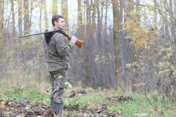 Людина в камуфляжі і зі зброєю в лісовому поясі на весняному полюванні — стокове фото