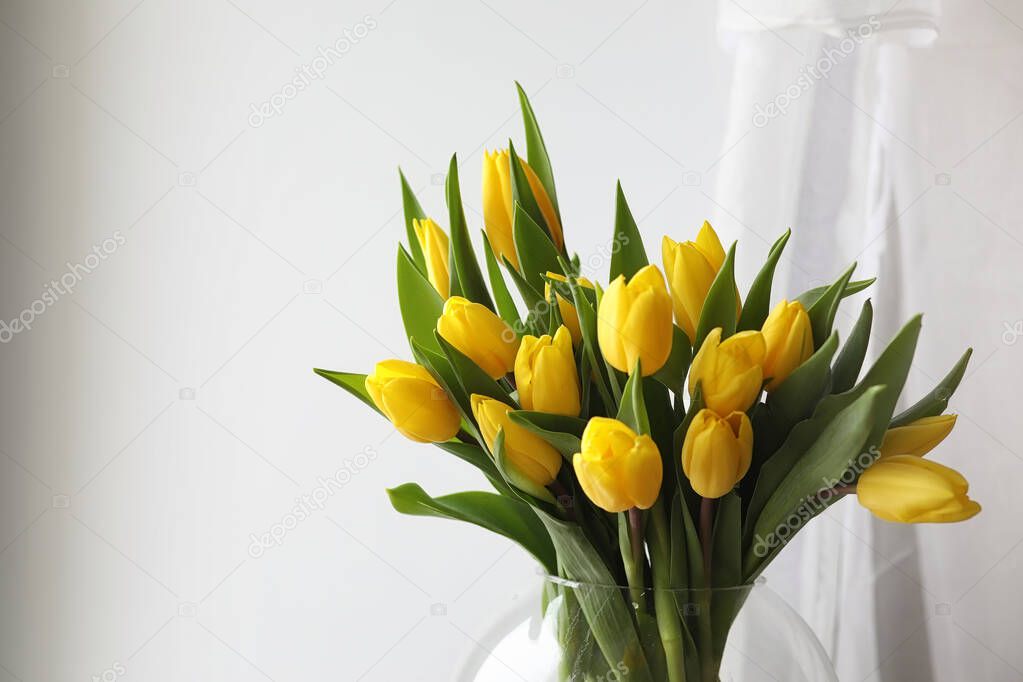 A bouquet of yellow tulips in a vase on the windowsill. A gift t