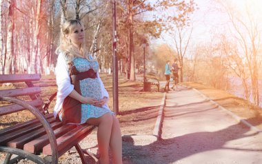 Hamile kız parkta bir yürüyüş. CI karnından kızla