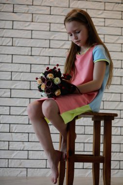 küçük kız bir sandalyede oturuyor