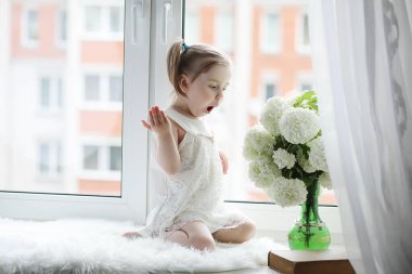 Küçük bir kız kenarında oturuyor. Bir buket çiçek