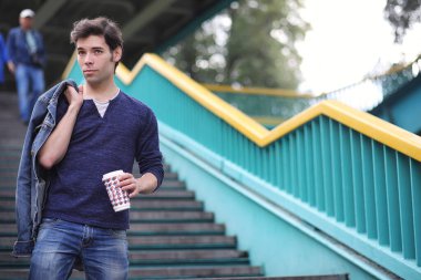 Genç bir adam öğle yemeği zamanında parkta yürür. Bir adam yürüyüşe çıktı. 