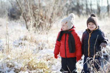 Kış parkında oynayan kalın elbiseli şirin çocuklar. 