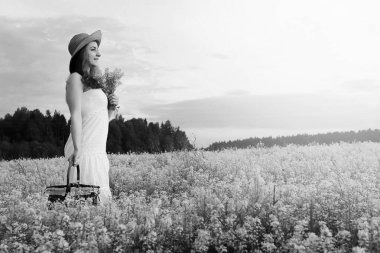 şapkalı genç kızın tek renkli resmi büyük bir çiçek tarlasında duruyor.