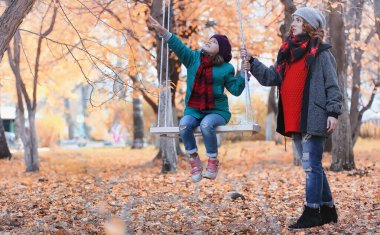 Kız sonbahar şehir parkında yaprak düşer. Genç güzel wi anne