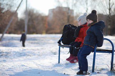 Kış parkında oynayan kalın elbiseli şirin çocuklar. 