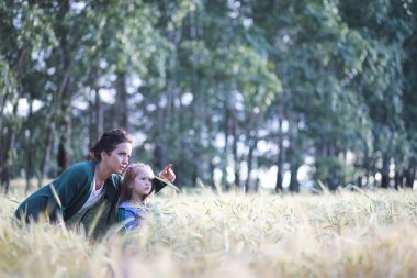 Genç anne yürüyerek buğday alanları içerisinde