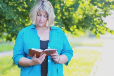 Parktaki kadın elinde kitapla yeşil ağaç 