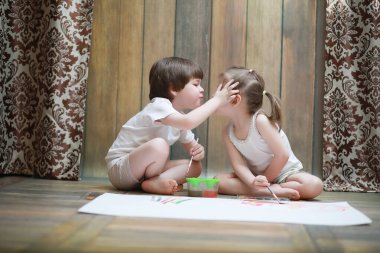 Küçük çocuklar büyük bir kağıda boya