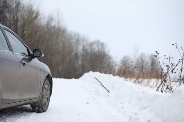 Tarlalarda karlı bir kış yolunda araba.
