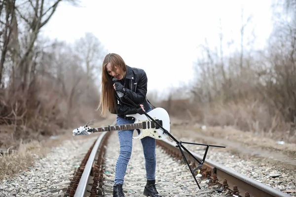 Een rock muzikant meisje in een leren jas met een gitaar — Stockfoto