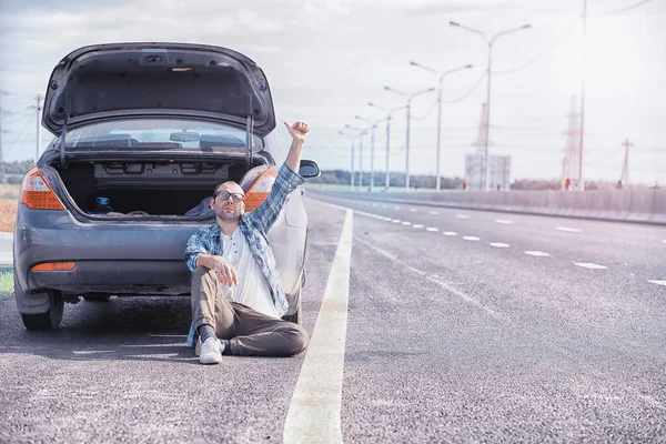 Ersätter hjulet på en bil på vägen. En man som utför däckarbete — Stockfoto