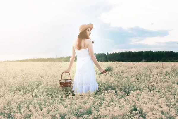 Дівчина в білій сукні в полі жовтих квітів, що розпускаються — стокове фото