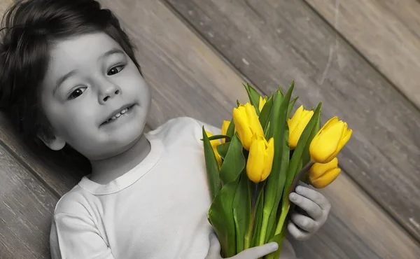 Egy kis gyerek egy-egy csokor sárga tulipánok. Egy fiú, egy ajándék — Stock Fotó